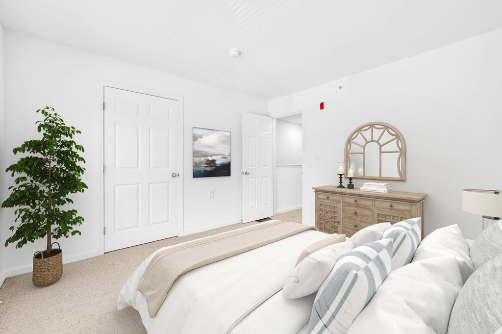 A bedroom with a bed, dresser, and a plant.