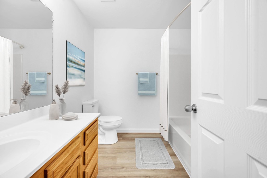 A bathroom with a toilet, sink, and a painting on the wall.
