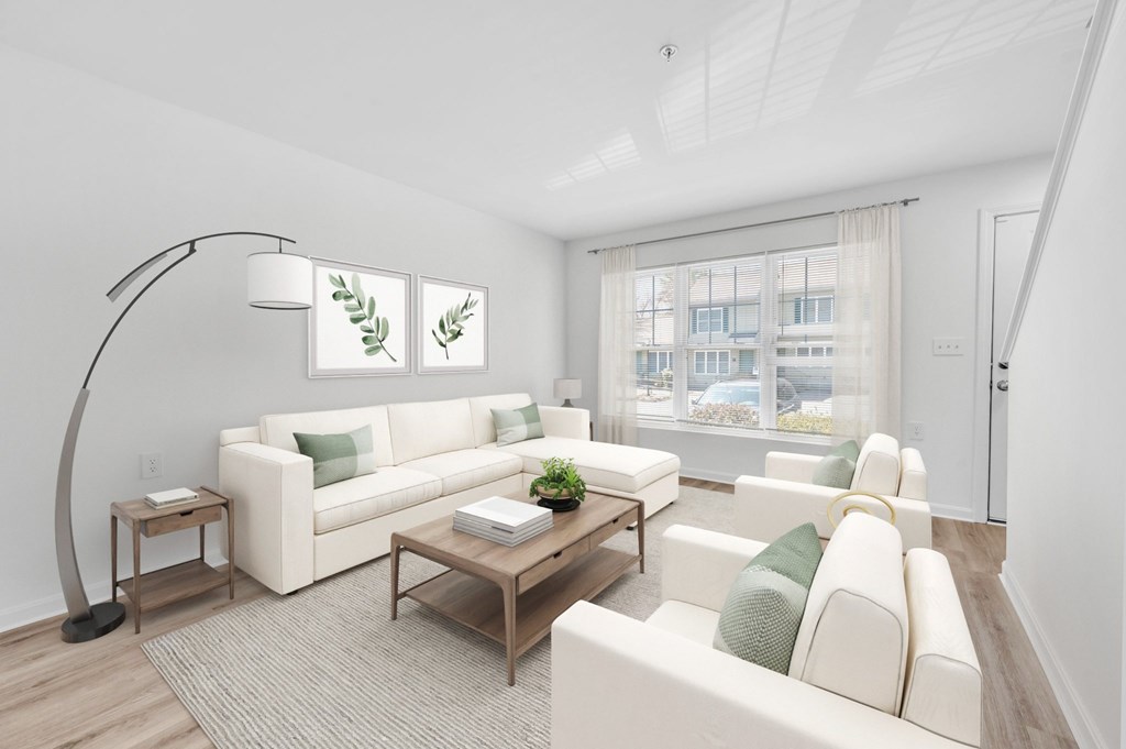 A living room with a white couch, a wooden coffee table, and a floor lamp.