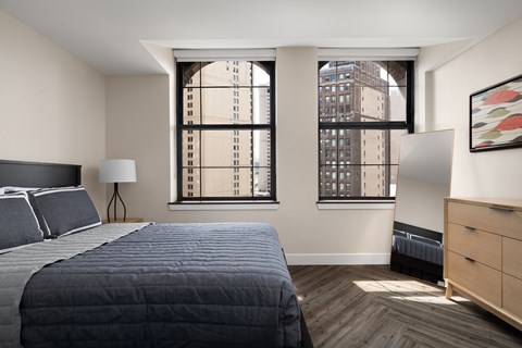a bedroom with a bed and two windows