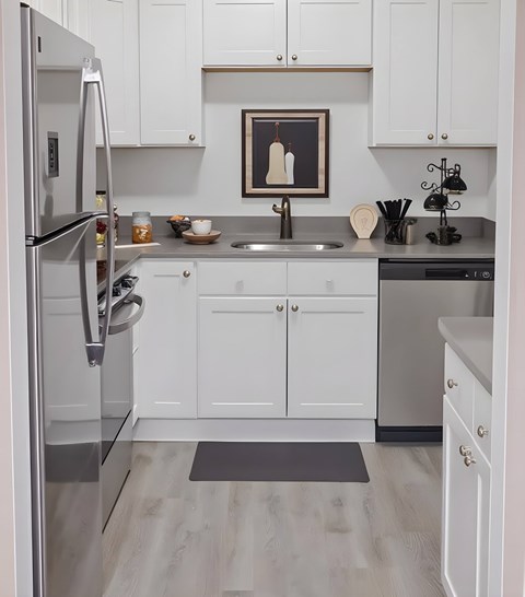 A modern kitchen with white cabinets and a stainless steel refrigerator.