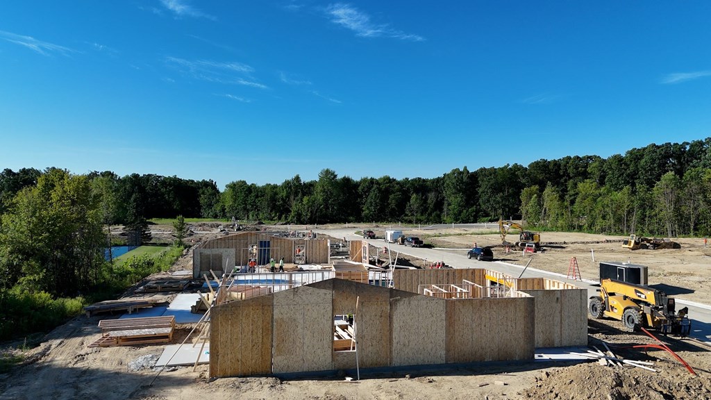 A construction site with a large building under construction and a yellow bulldozer in the foreground.