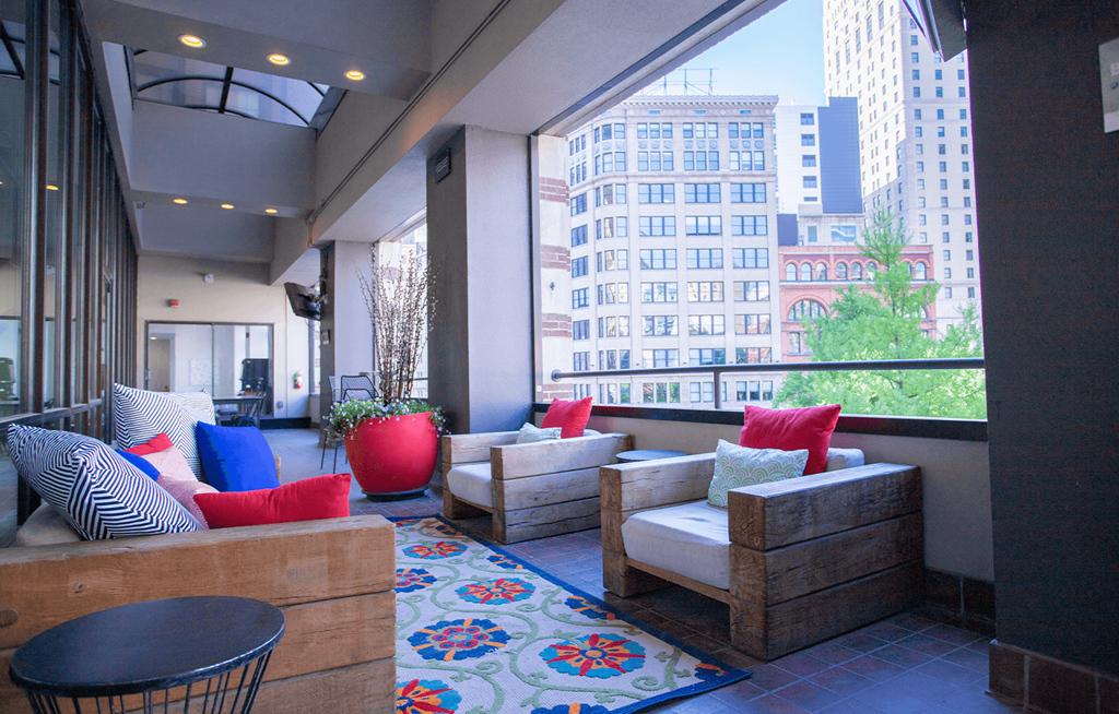 a seating area with couches chairs and a rug in front of a large window