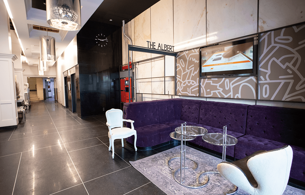 a purple couch and chairs in a lobby with a clock on the wall