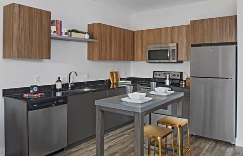 a kitchen with stainless steel appliances and a table with three stools