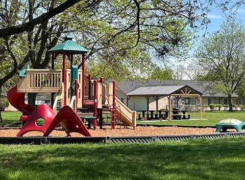 A playground with a red slide and a green roofed structure.