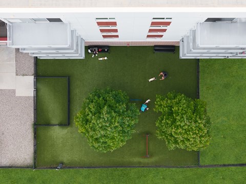 A man and a woman are playing badminton in a green yard.