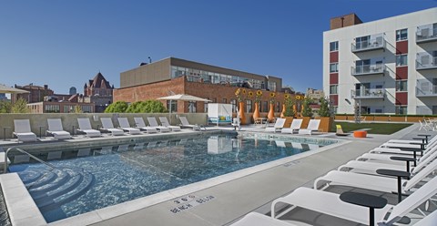 A pool with chairs around it and a building in the background.