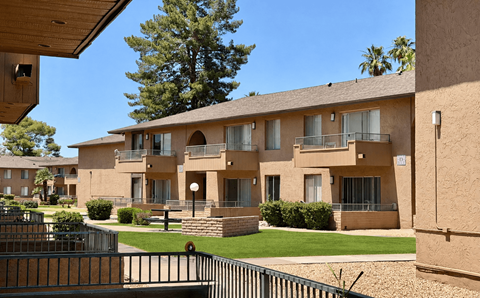 A row of apartment buildings with a tree in the background.