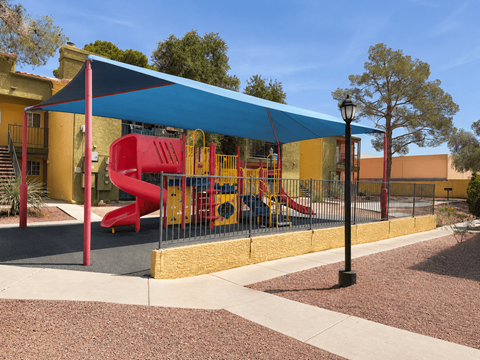 A playground with a red slide and a blue canopy.