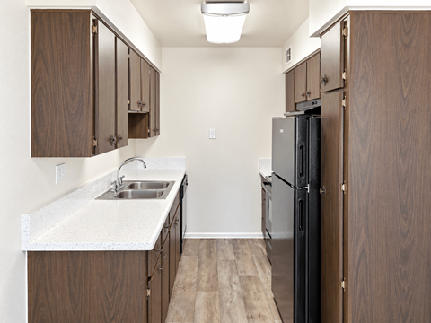 A kitchen with a black refrigerator and brown cabinets.
