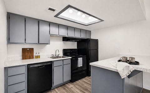 A modern kitchen with black appliances and grey cabinets.