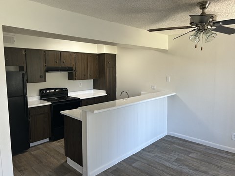 A kitchen with a white counter and a black fridge.