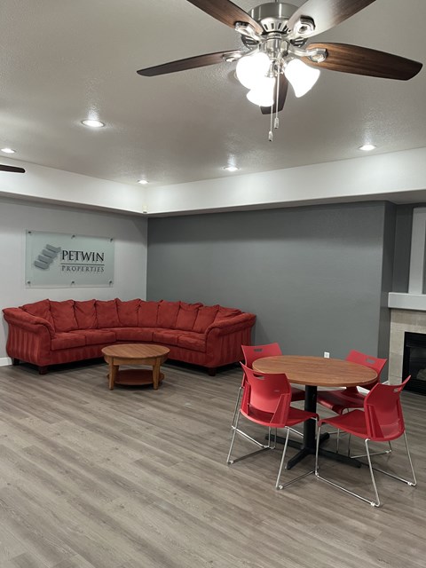 A living room with a red couch, a wooden table, and a ceiling fan.