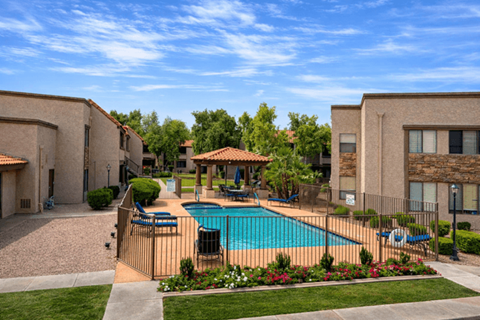 A swimming pool surrounded by a fence and a small garden.