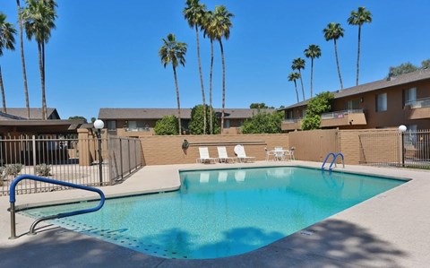 A swimming pool surrounded by palm trees and apartment buildings.