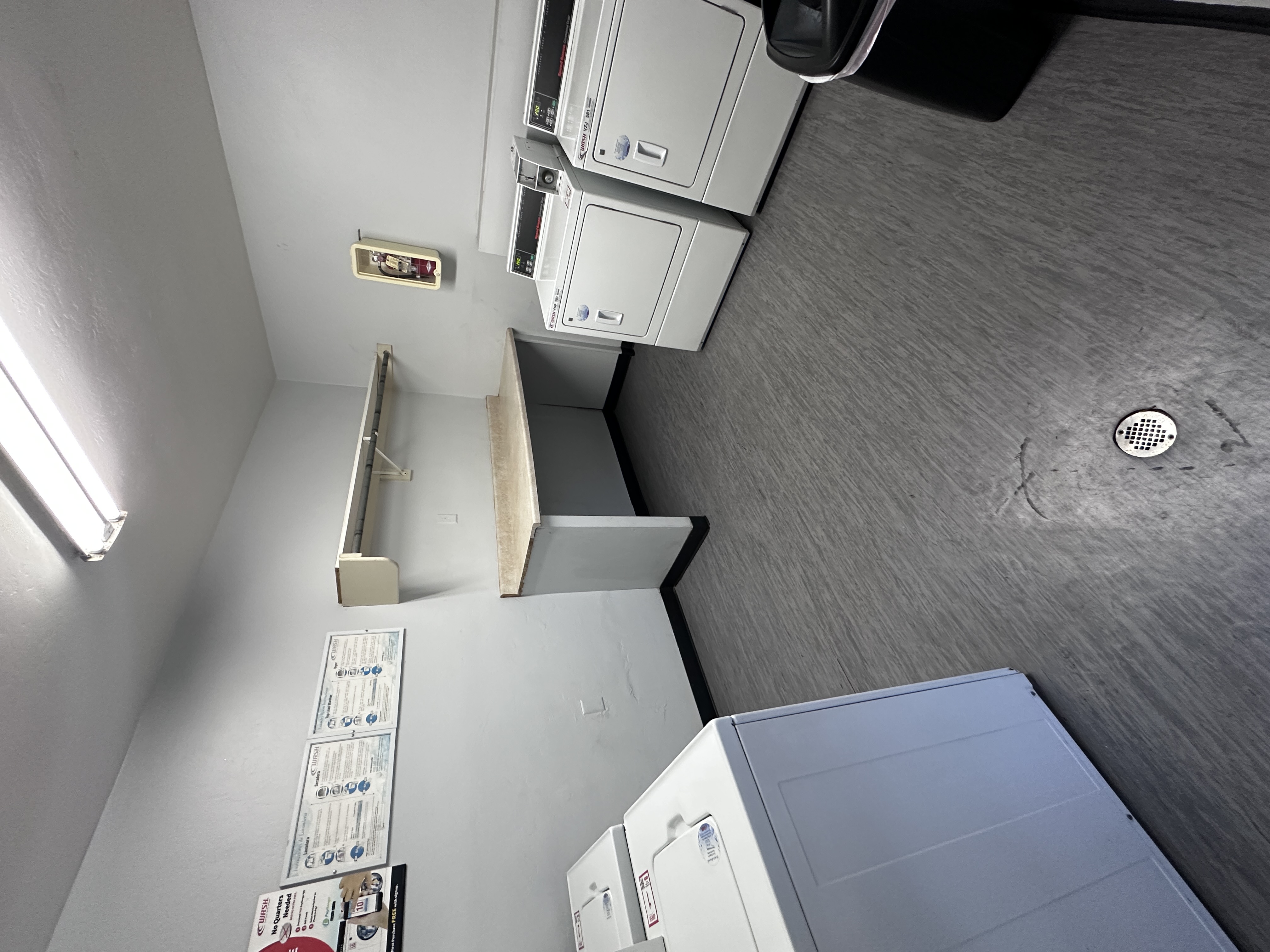A view of a room with a white wall and a grey floor.