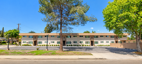 A large building with a brown roof and a parking lot in front.