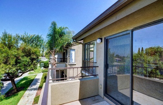 a house with a balcony overlooking a yard and trees