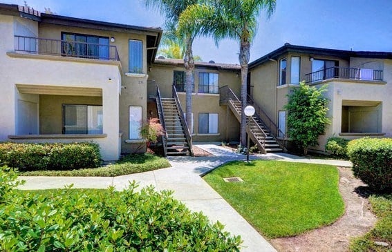 an apartment building with stairs and grass and trees