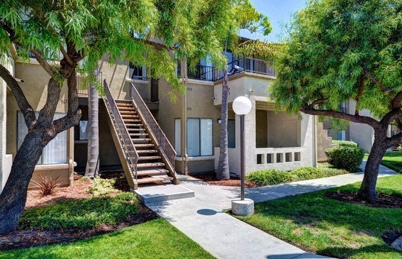 an apartment building with stairs and trees in front of it