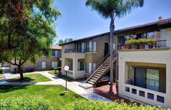 the backyard of an apartment building with a staircase and a lawn