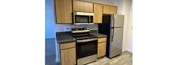 A kitchen with a black refrigerator and stainless steel appliances.