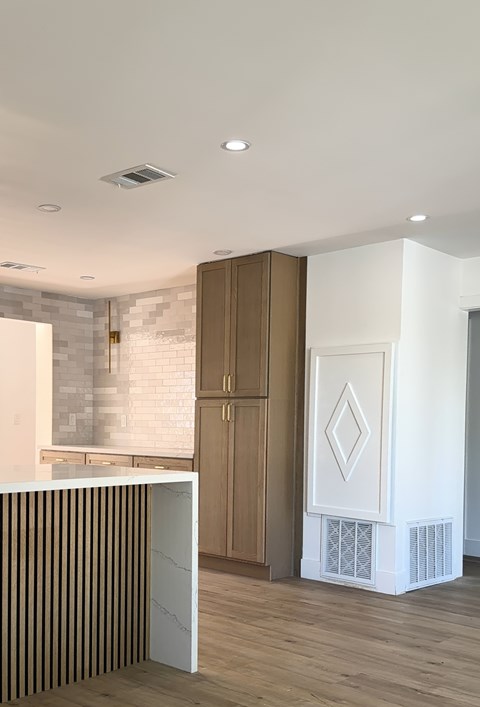 A kitchen with a white counter and wooden cabinets.