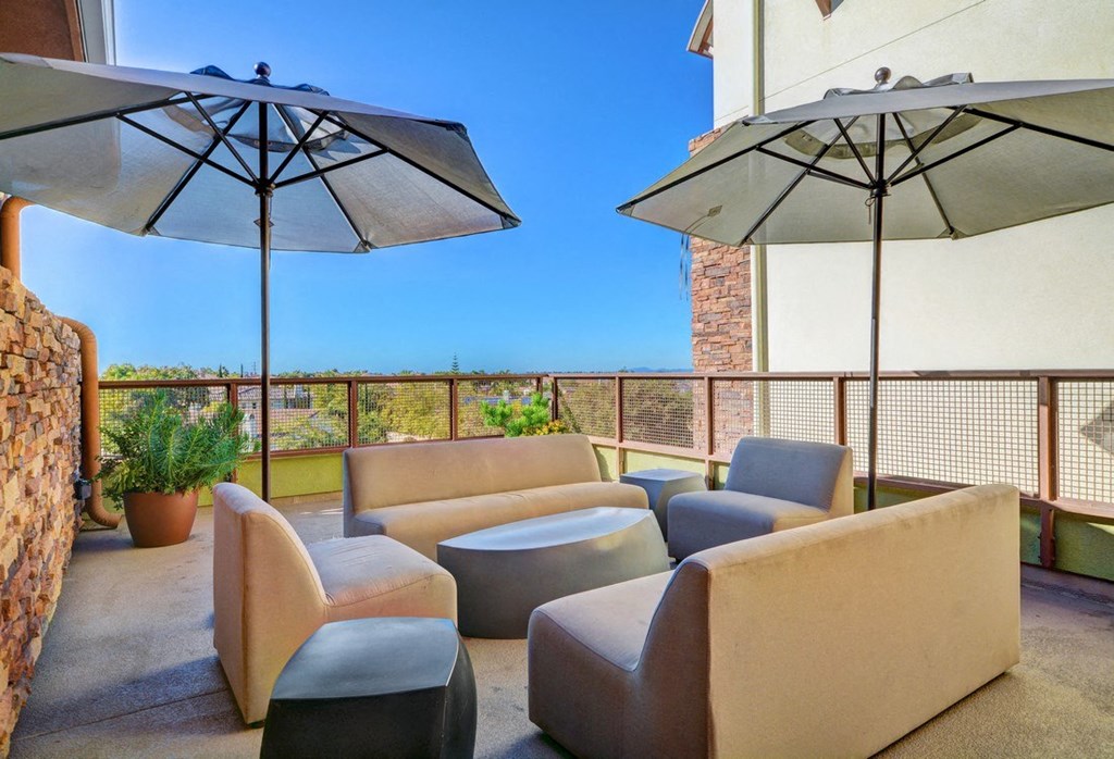 a patio with chairs and umbrellas on a balcony