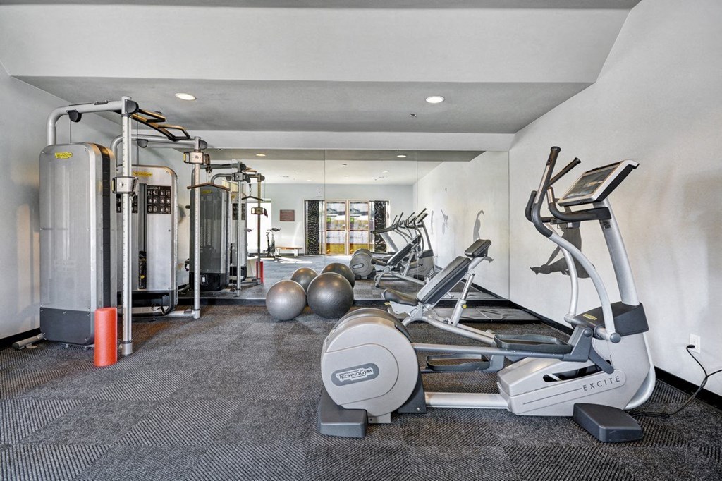 a gym with weights and cardio equipment on the floor and a water heater
