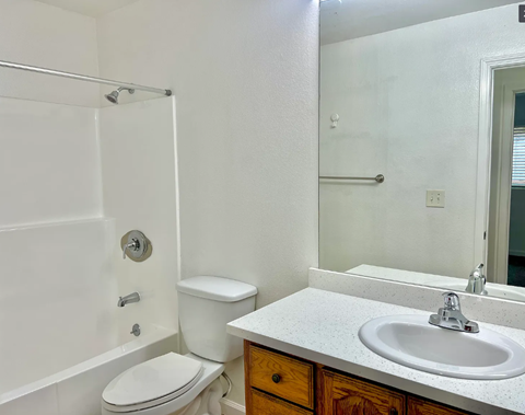 A white bathroom with a toilet, sink, and shower.
