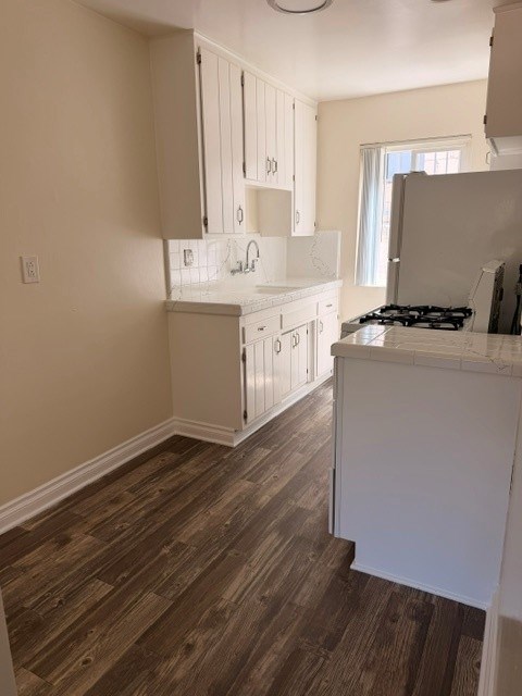 A kitchen with white cabinets and a wooden floor.