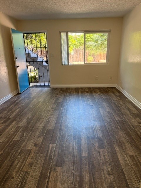 A room with wooden flooring and a window showing a fence outside.