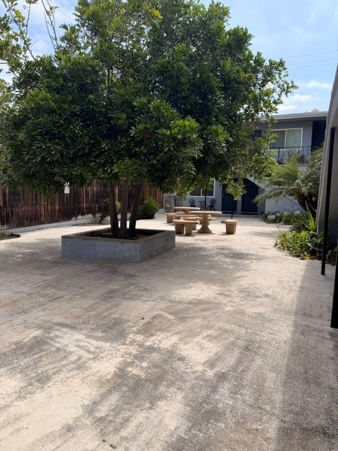 A concrete patio with a tree and a fire pit.