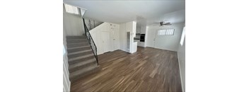 A room with wooden flooring and a staircase with a black railing.