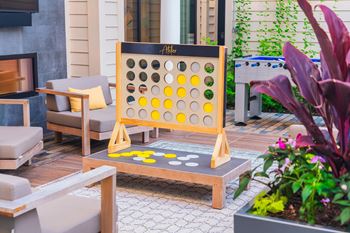 A wooden game of connect four is set up on a table outside.