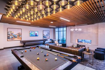 A pool table is in the middle of a room with a couch and a bench.