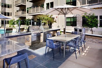 A patio with a table and chairs and a grill.