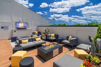 A modern outdoor seating area with a television screen and comfortable seating options.