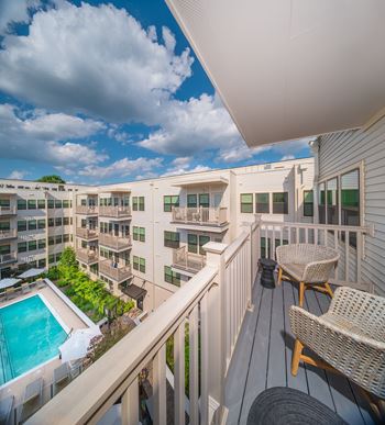A balcony with chairs and a pool in the background.