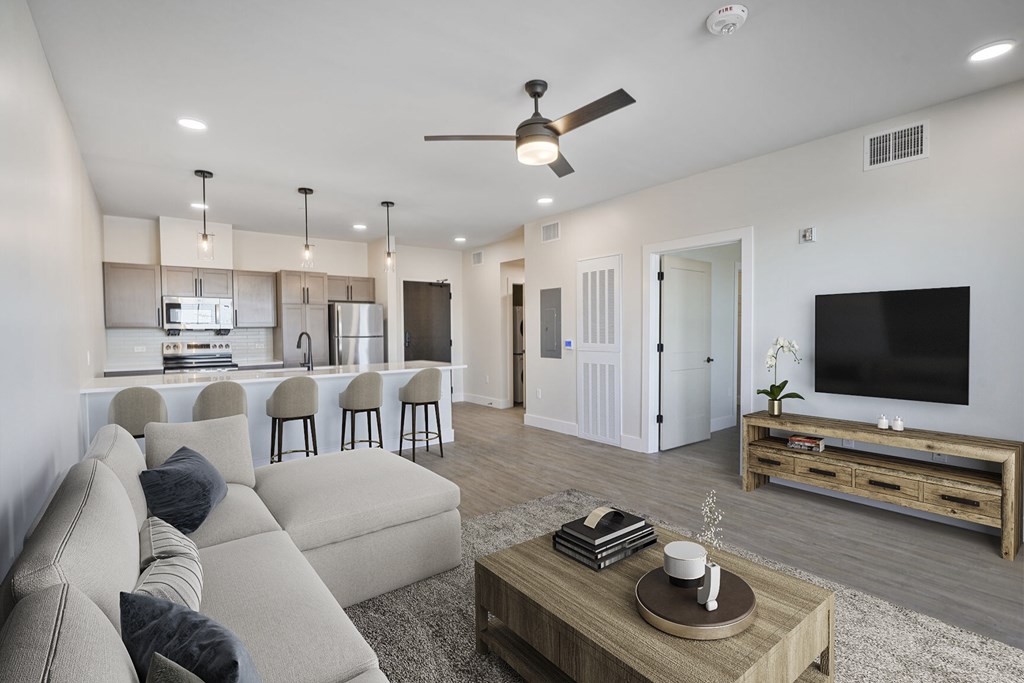 A modern living room with a beige sofa, a wooden coffee table, and a flat-screen TV.