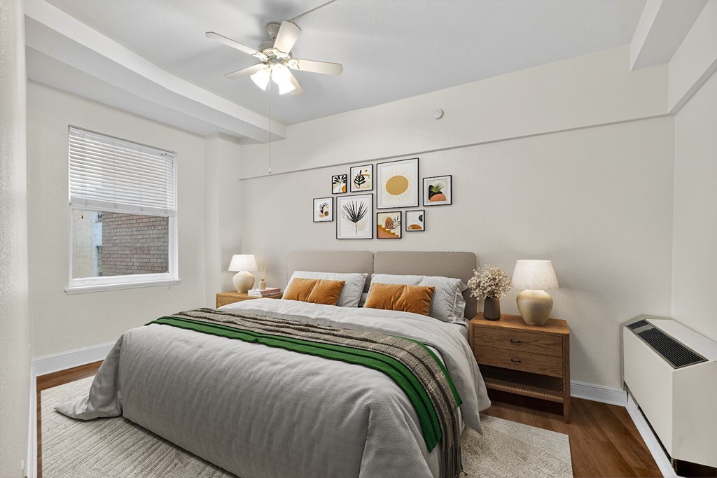 A bedroom with a bed, nightstands, and pictures on the wall.