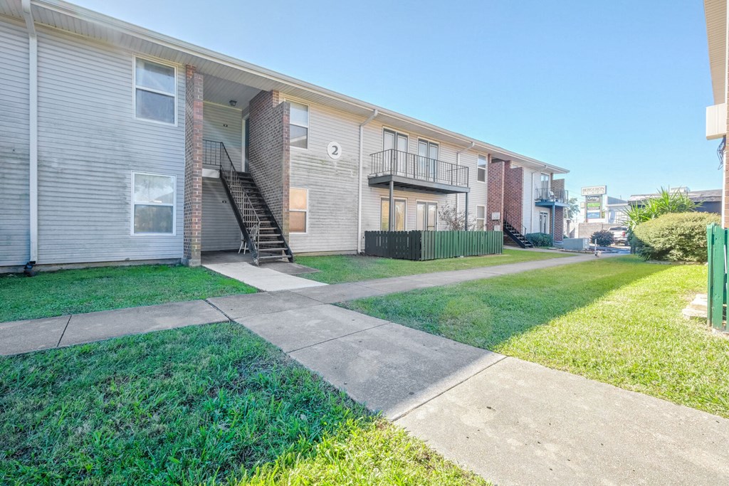 Apartment complex with a green fence and a clear sky.