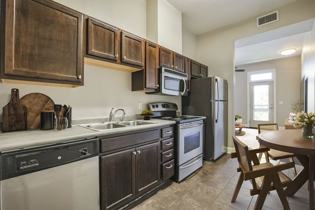 A kitchen with dark wood cabinets and stainless steel appliances.