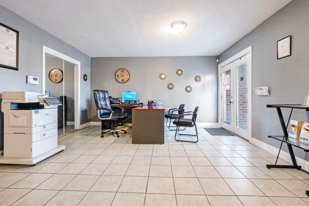 A room with a desk, chairs, and a clock on the wall.