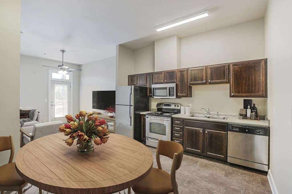 A kitchen with a wooden table and chairs and a vase of flowers on it.