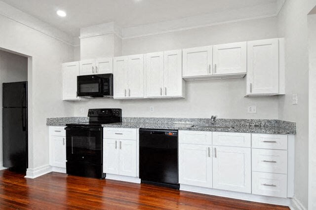 a kitchen with white cabinets and black appliances
