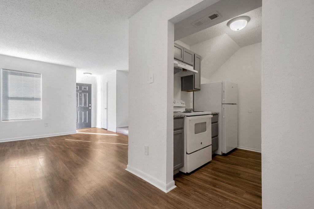 A kitchen with white appliances and wooden floors.