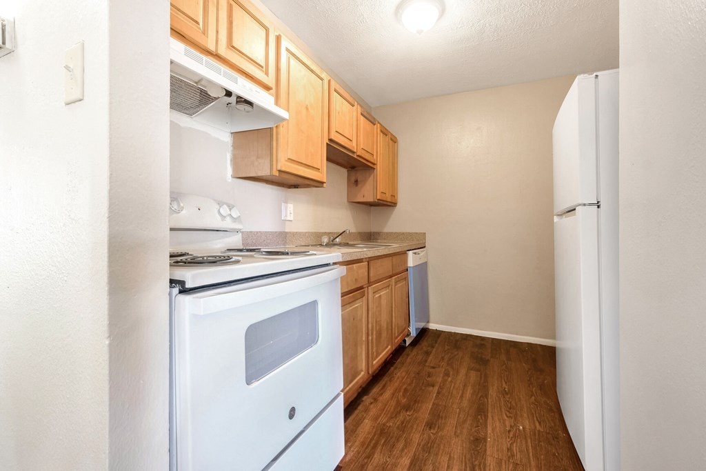 A kitchen with white appliances and wooden cabinets.