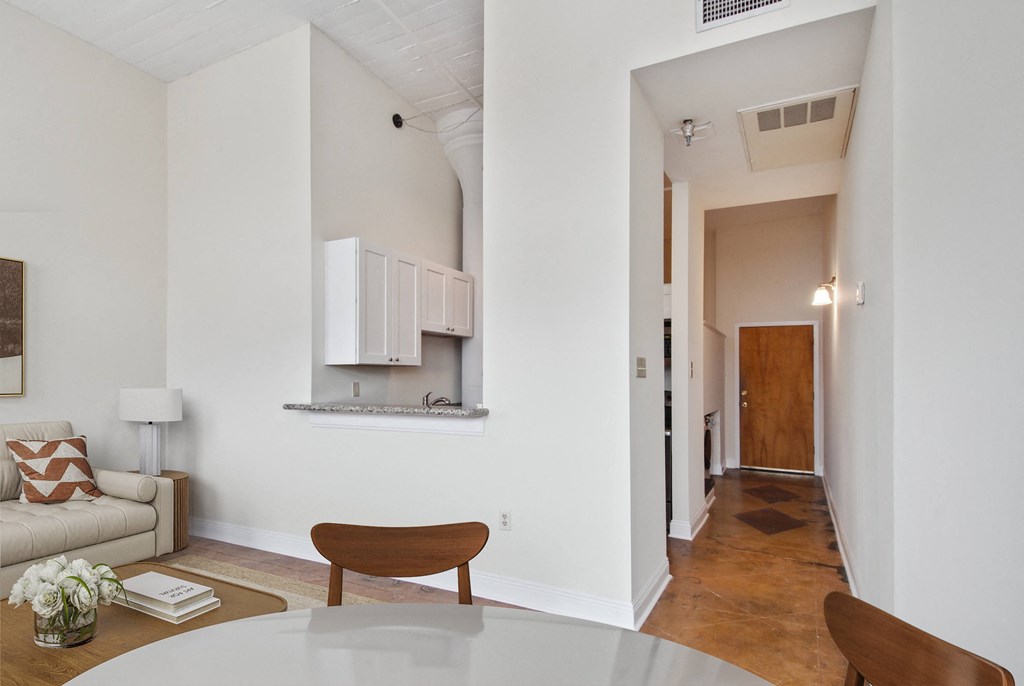 a living room and dining room with a white table and a hall to a kitchen